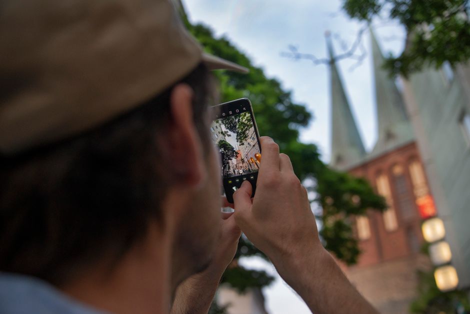 A person captures iconic Berlin church towers using a smartphone, outdoors.